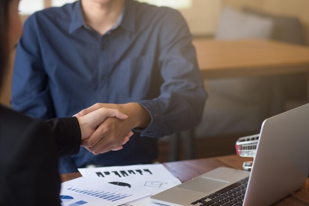 Mittlerer Abschnitt von Geschäftskollegen, die sich am Tisch im Büro ein Handschlag geben