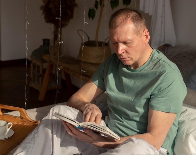 Mittlerer Alter reifer Mann, der Buch im gemütlichen Haus, Tageslicht liest.