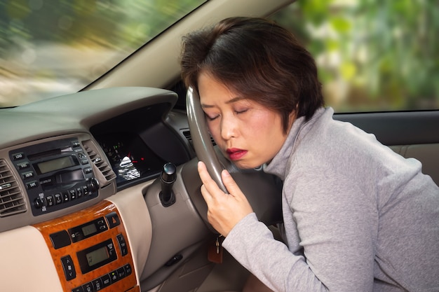 Foto mittlerer asiatischer erwachsener schläfrig hinter lenkrad. risiko bei transportunfall.