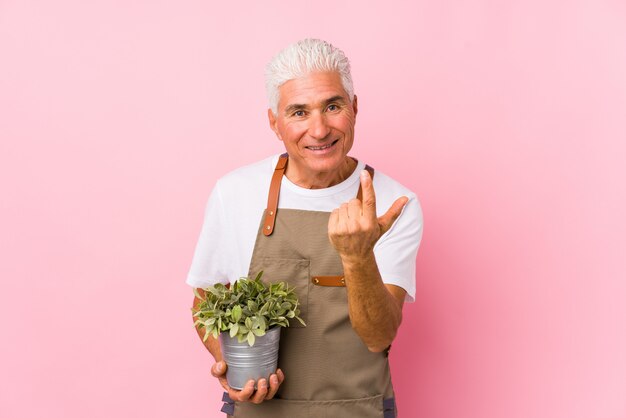 Mittlerer gealterter Gärtnermann lokalisiertes Zeigen mit dem Finger auf Sie, als ob Einladung näher kommen.