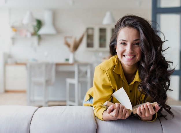 Mittlerer Schuss glückliche Brunettefrau mit Buch