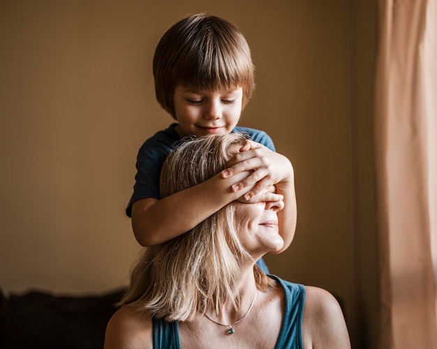 Foto mittlerer schuss junge, der die augen der frau bedeckt