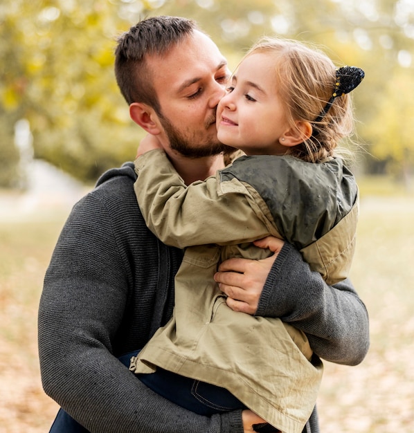 Mittlerer Schuss Vater küsst Mädchen auf Wange