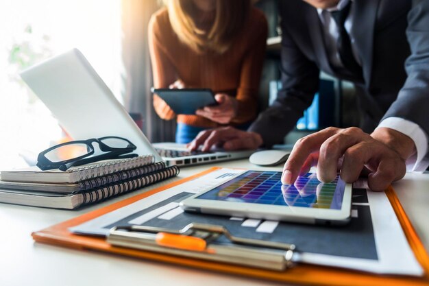 Mittlerer Teil der Kollegen verwendet Technologien am Schreibtisch im Büro