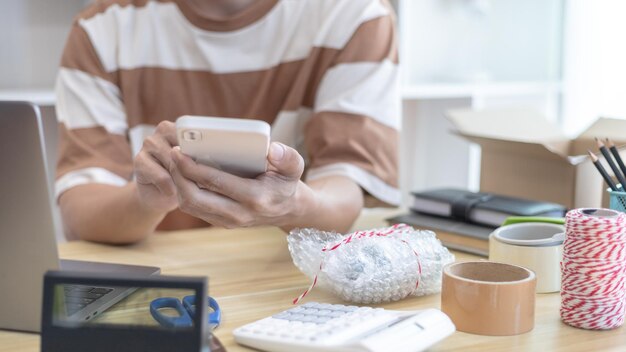 Mittlerer Teil einer Frau, die am Tisch ein Mobiltelefon benutzt