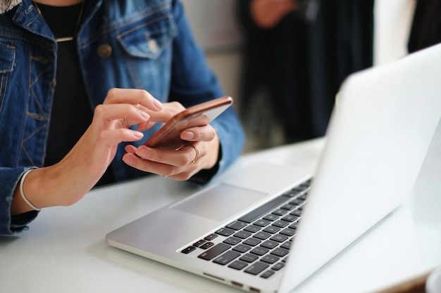 Foto mittlerer teil einer frau mit telefon und laptop auf dem tisch