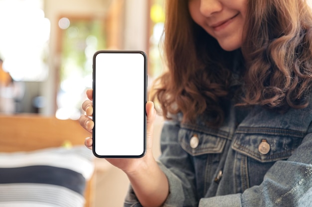Mittlerer Teil einer lächelnden Frau, die ein Mobiltelefon zeigt