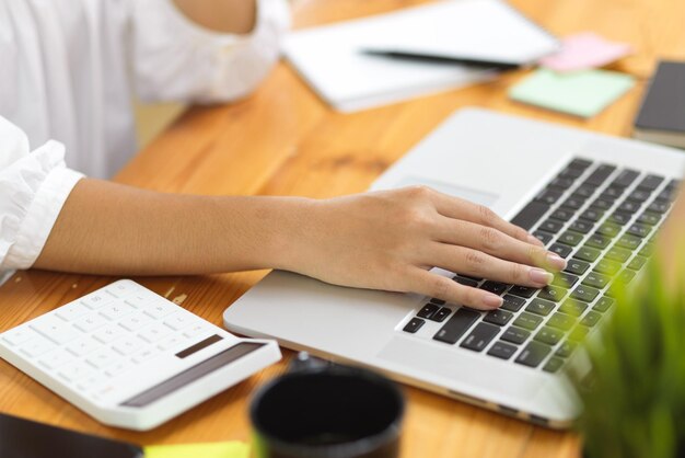 Mittlerer Teil einer Person, die einen Laptop auf dem Tisch benutzt