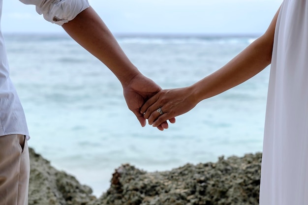 Mittlerer Teil eines Paares, das sich am Meer die Hände hält