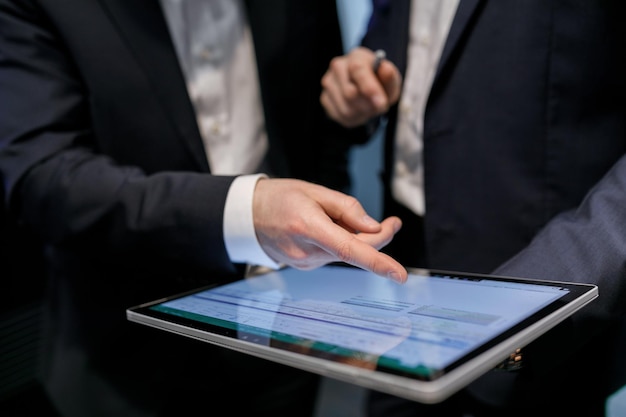 Mittlerer Teil von Kollegen diskutiert über ein digitales Tablet