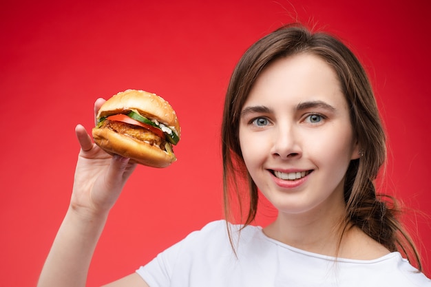 Mittleres Nahaufnahmeporträt der schönen jungen Modefrau, die frisches appetitliches Sandwich beißt