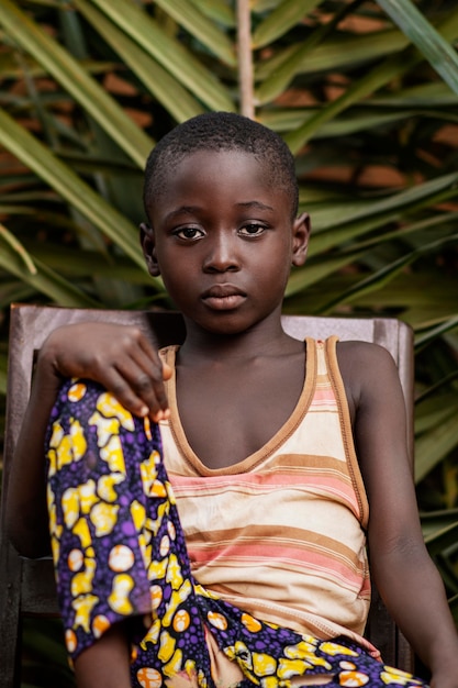 Foto mittleres schuss afrikanisches kind, das auf stuhl aufwirft