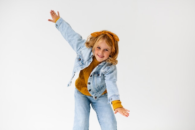 Foto mittleres schuss-smiley-mädchen, das im studio aufwirft