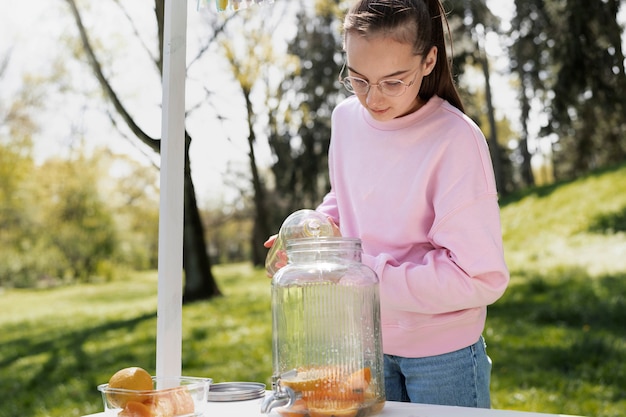 Mittleres Schussmädchen, das draußen Limonade macht