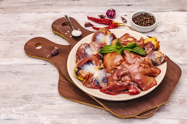 Miudezas de frango cru fresco: coração, fígado, estômago com especiarias secas, sal marinho, pimenta na mesa de madeira