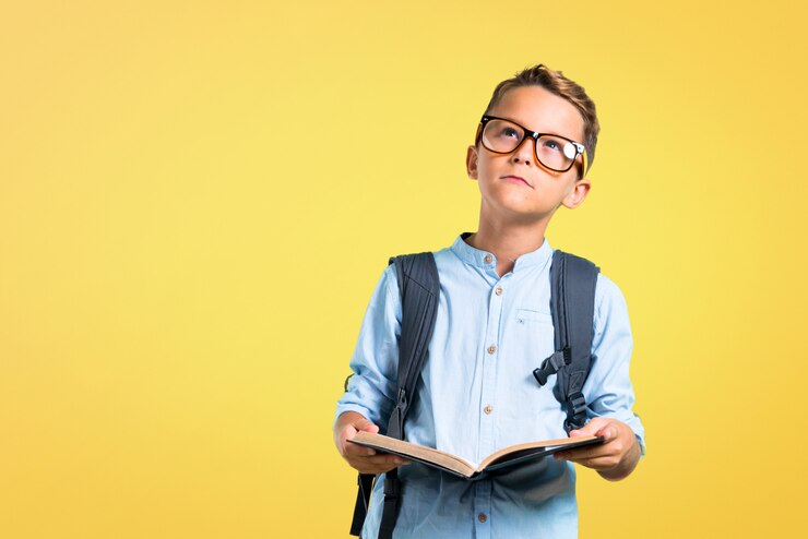 Foto miúdo do estudante com a trouxa e os vidros que guardam um livro no fundo amarelo. de volta à escola