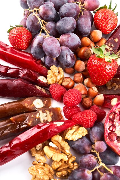 Mix de Churchkhela, frutas, bagas e nozes em uma mesa branca, doces caucasianos