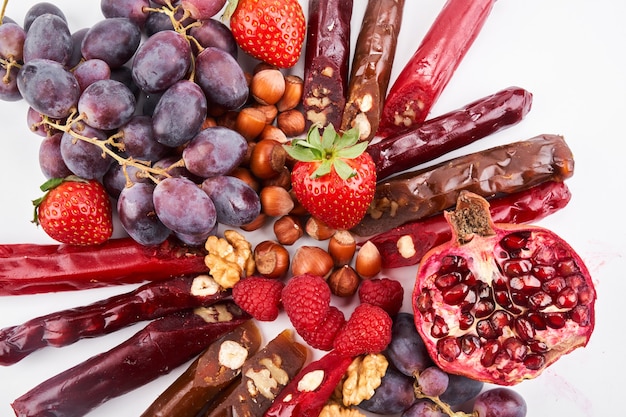 Mix de Churchkhela, frutas, bagas e nozes em uma mesa branca, doces caucasianos