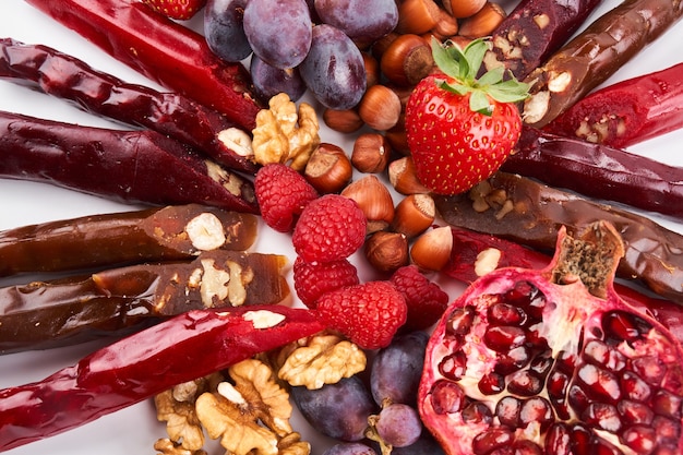 Mix de Churchkhela, frutas, bagas e nozes em uma mesa branca, fundo de alimentos, doces caucasianos