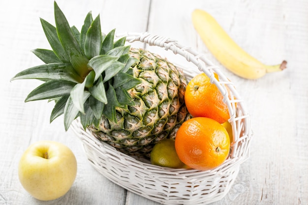 Mix de frutas frescas na cesta branca na mesa de madeira