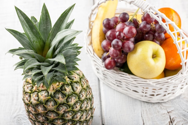 Mix de frutas frescas na cesta branca na mesa de madeira