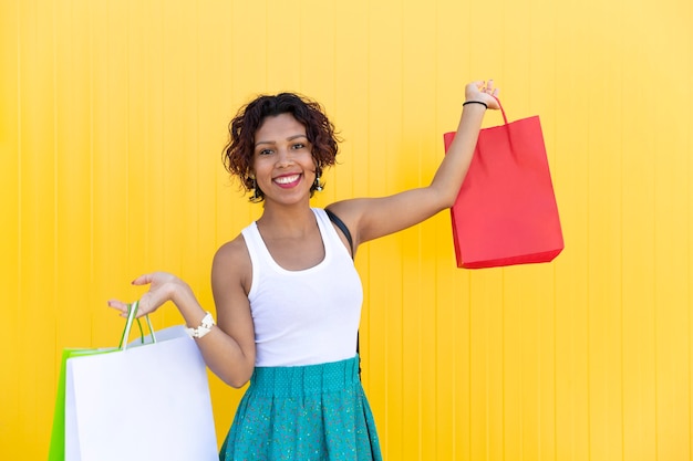 Mixed Race Girl lächelt, als sie ein paar Einkaufstaschen in den Händen hält.