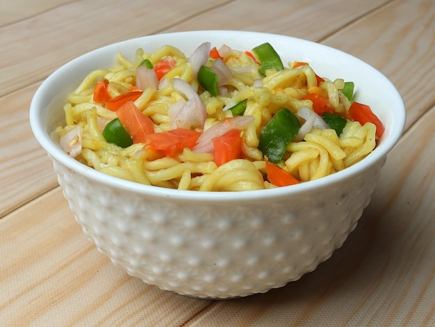 Mixed Veg Maggie Noodles Instant-Nudeln, die mit Gemüse gekocht und dann in einer Schüssel über einem selektiven Fokus aus rustikalem Holz serviert werden