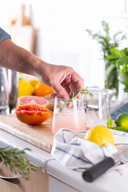 Mixólogo haciendo cócteles refrescantes con agua carbonatada en casa