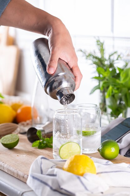 Mixólogo haciendo cócteles refrescantes con agua carbonatada en casa