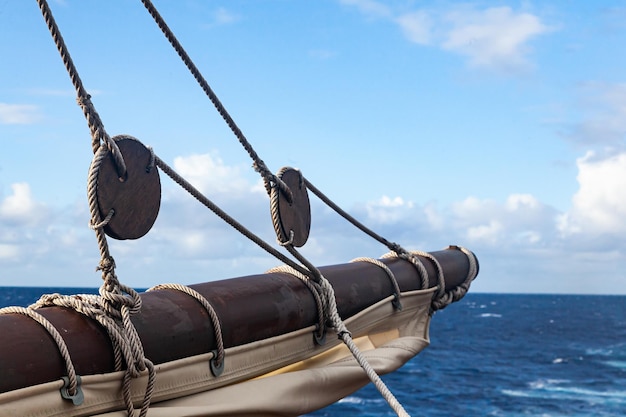 Mizzen-Mast eines alten Holzschiffes mit einem darauf gefalteten Segel aus Holzrollen und Seilen