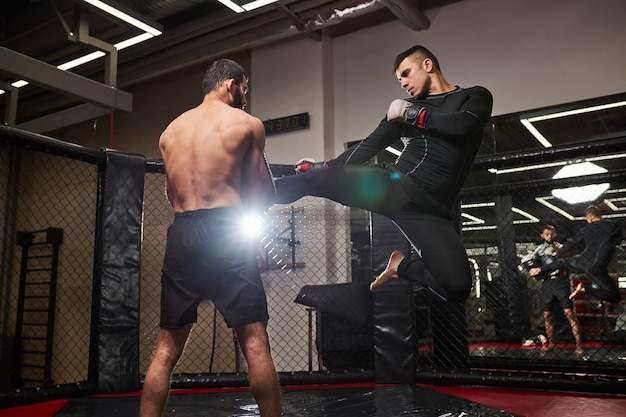 MMA. Zwei professionelle Boxer boxen, fit muskulöse kaukasische Athleten kämpfen. Konzept für Sport, Wettbewerb, Aufregung und menschliche Emotionen. Seitenansicht auf Männer in Bewegung. Kampf ohne Regeln