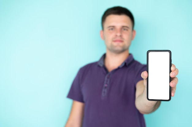 Mobile Anwendung Glücklicher Mann Digitaltechnik Lächelnder, defokussierter Kerl, der einen leeren Smartphone-Bildschirm zeigt, der isolierten blauen Kopierraum darstellt
