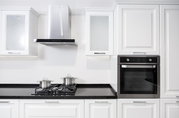 Mobília de cozinha branca brilhante com utensílios de cozinha e panelas em um fogão