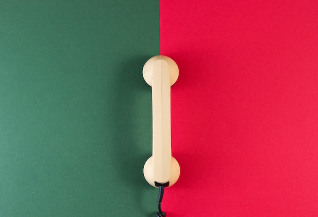 Mobilteil eines Retro-Telefons auf einer rot-grünen Oberfläche.
