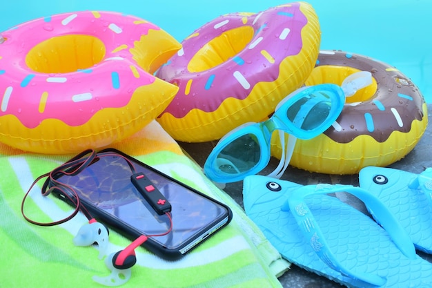 Foto mobiltelefon mit hausschuhe und aufblasbaren ringen am pool