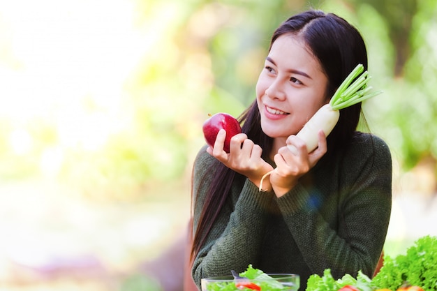 Moça bonita asiática que come o vegetal de salada