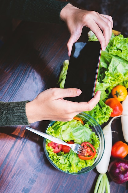 Moça bonita asiática que come o vegetal de salada