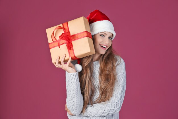 Moça bonita com chapéu de Natal segurando uma caixa de presente