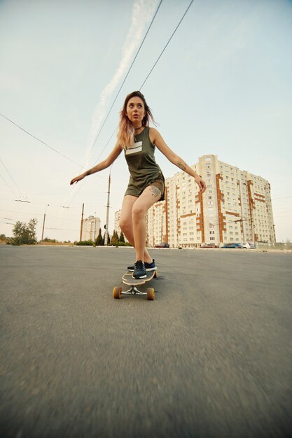 Moça bonita com tatuagens que montam no longboard