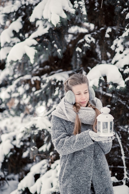 Moça bonita na floresta do inverno que guarda a decoração