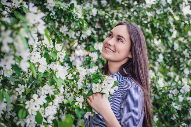 Moça bonita perto de macieiras florescendo na primavera