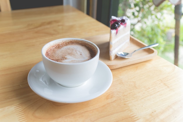 Moca de café caliente con leche de espuma y pastel de arándanos en café de campo