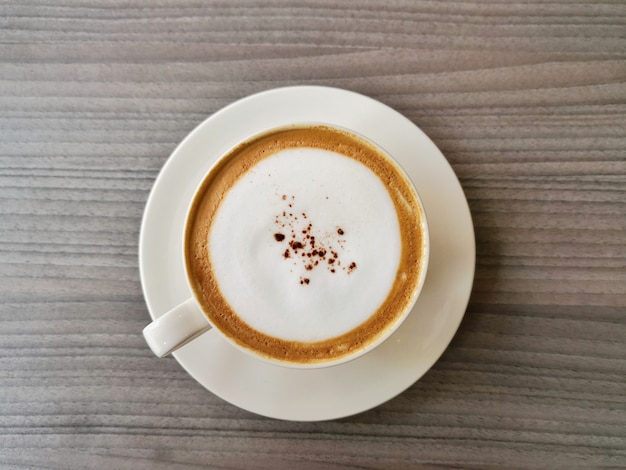 Foto moca del café en una taza blanca en una tabla de madera negra.