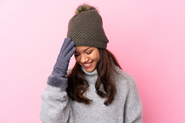 Moça com chapéu do inverno sobre a parede cor-de-rosa rindo