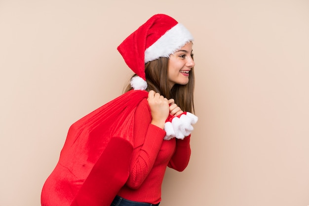 Moça com chapéu do Natal sobre a parede isolada