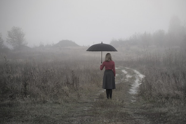 Foto moça com guarda-chuva no campo do outono