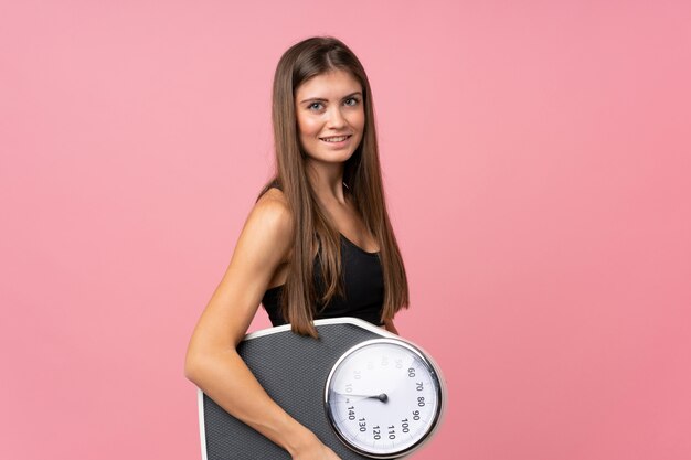 Moça com máquina de pesagem sobre rosa isolado