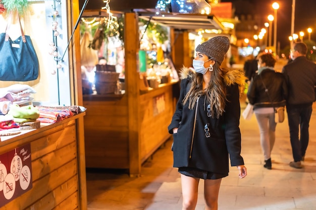 Moça com máscara facial visitando o mercado de natal