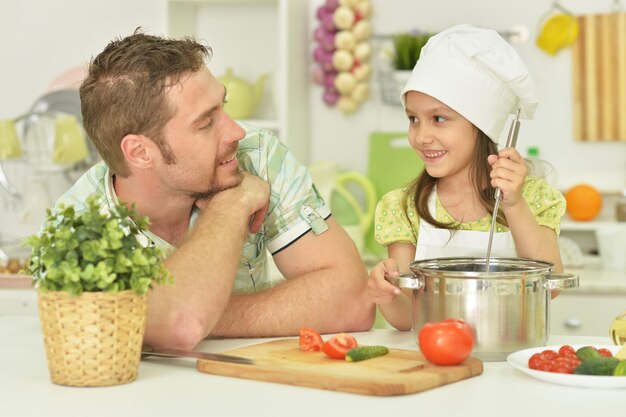 Moça com o pai cozinhando na cozinha