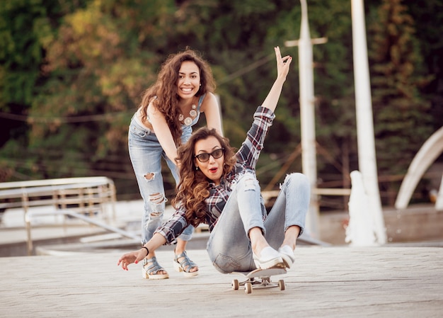 Moça com skate na parede cinza grande.